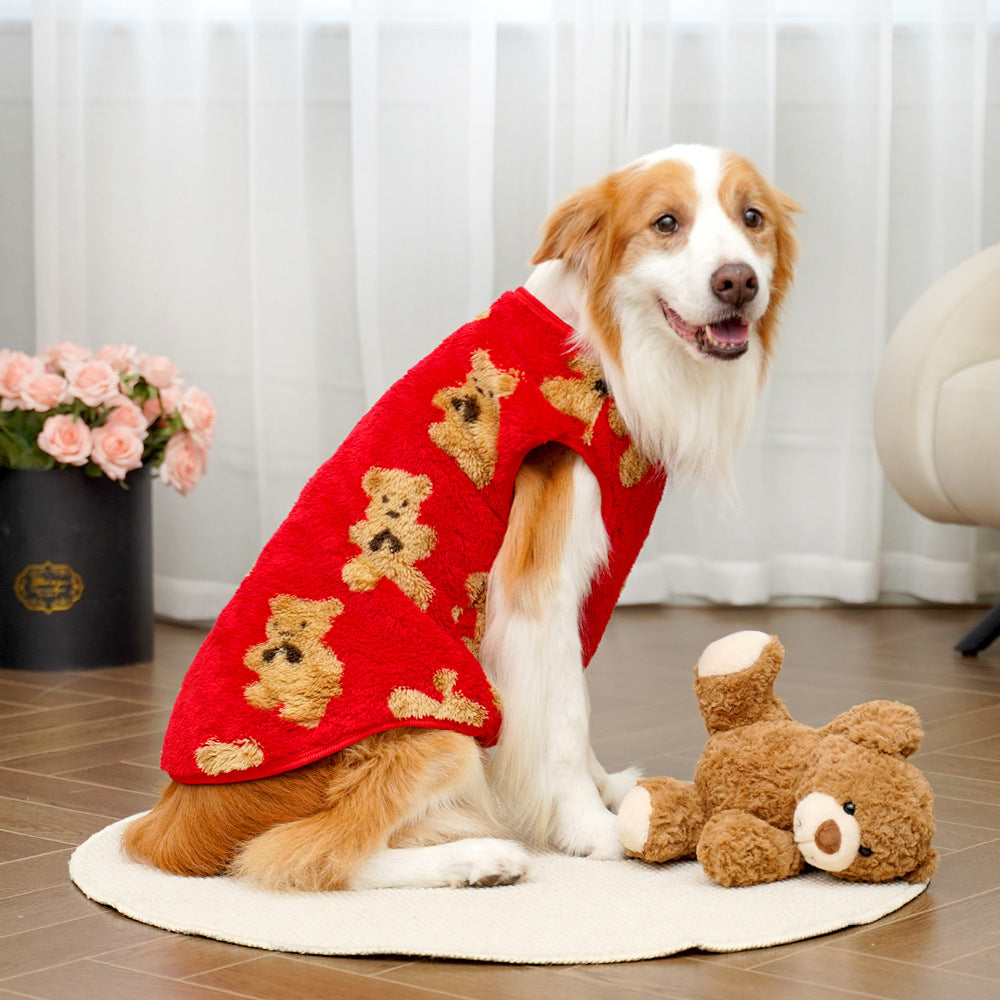 Dog wearing a red sweater with teddy bear patterns sitting on a wooden floor.