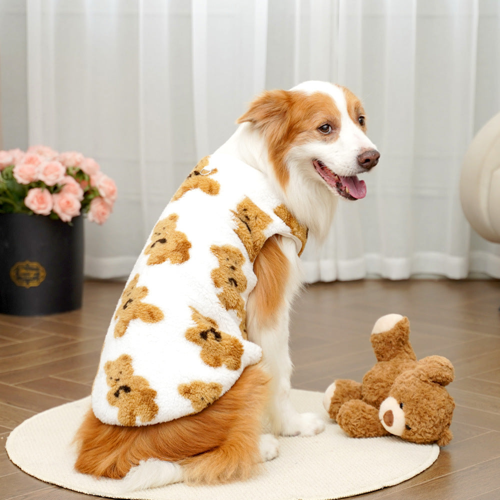 Dog wearing a teddy bear patterned sweater sitting on a wooden floor with a teddy bear beside it.