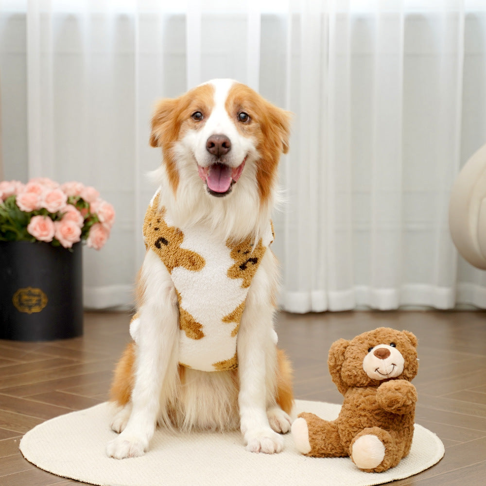 Dog wearing a sweater with teddy bear design sitting on a rug next to a teddy bear.
