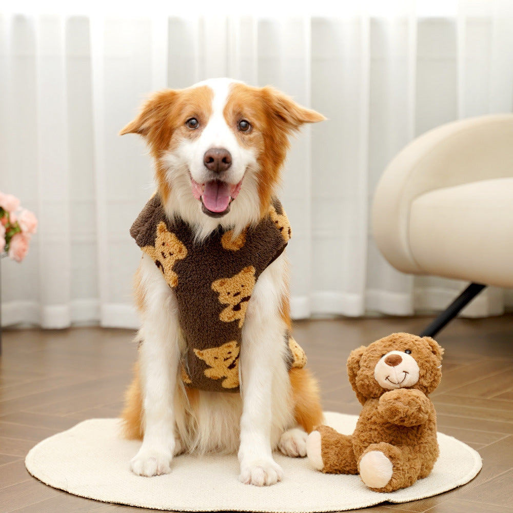Dog wearing a brown sweater with a teddy bear toy on a wooden floor.