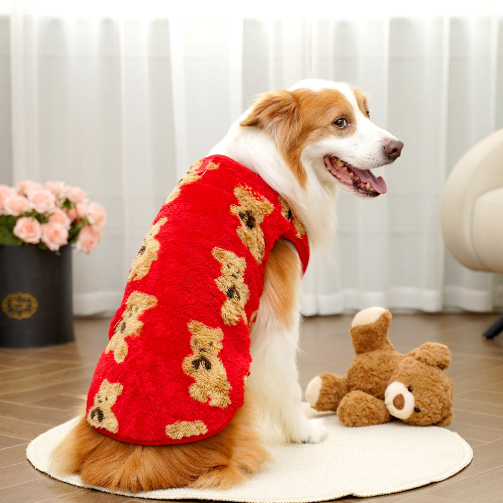 Dog wearing a red sweater with teddy bear patterns, sitting on a wooden floor.