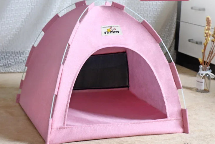 Pink pet tent on a light tan carpet with a white textured wall in the background.