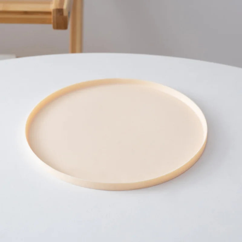 Round beige ceramic plate on a white surface with a neutral background