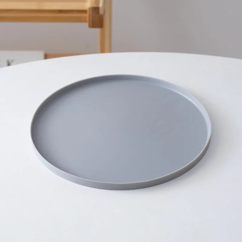 Gray plate on a white surface with a blurred wooden chair in the background