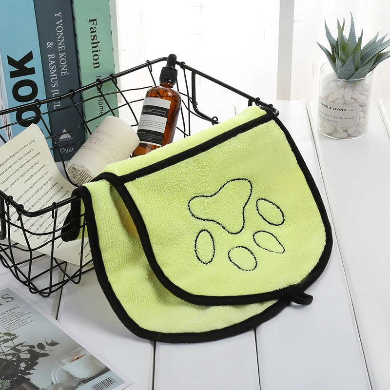 yellow  towel with paw prints on a white surface with books and a plant in the background