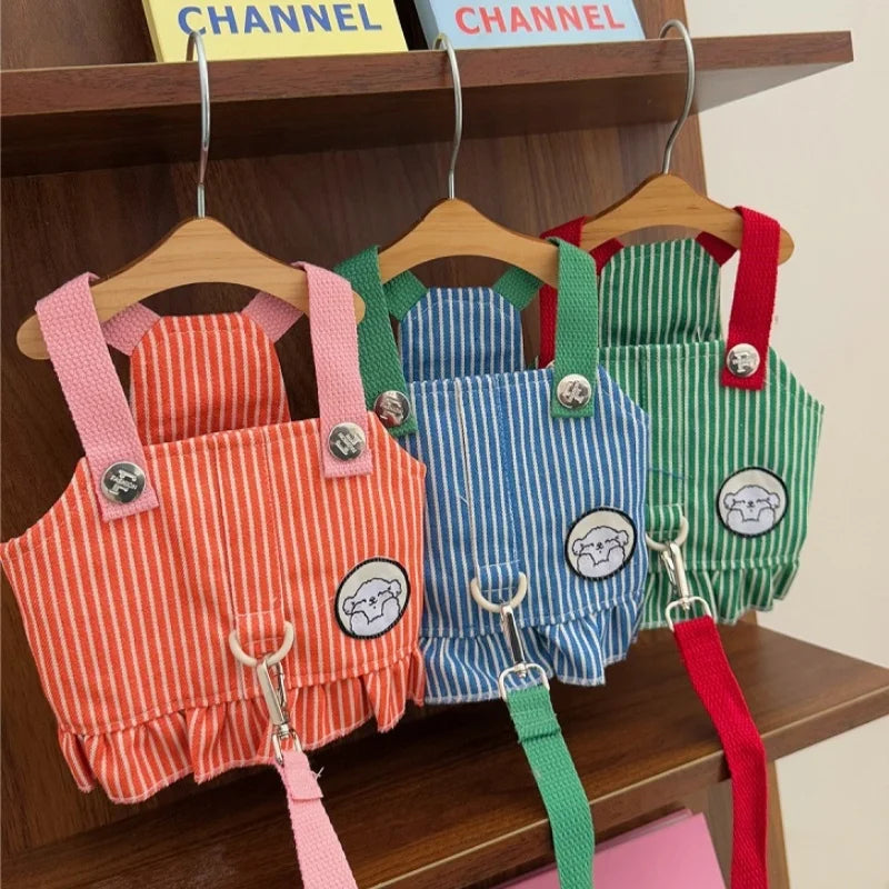 three overalls in different colors hanging on a wooden shelf.