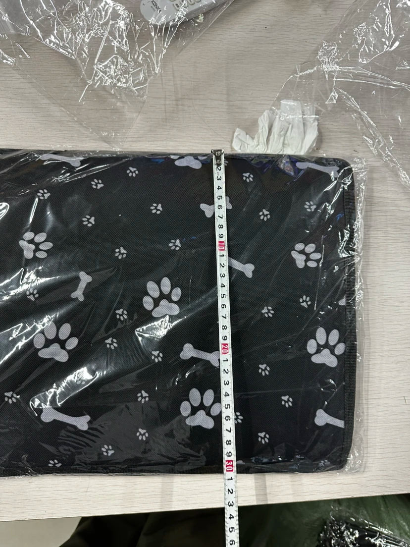 Black pet carrier with paw and bone patterns on a transparent plastic sheet, measured with a ruler.