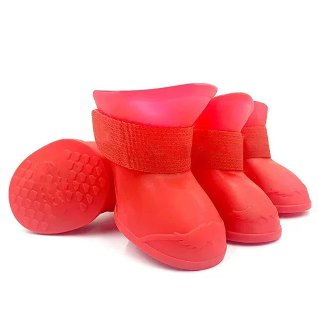 Set of red rubber dog boots with textured soles on a white background