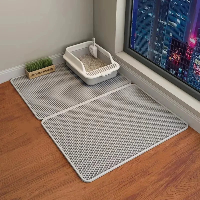Cat litter box with mat on a wooden floor next to a window with cityscape view
