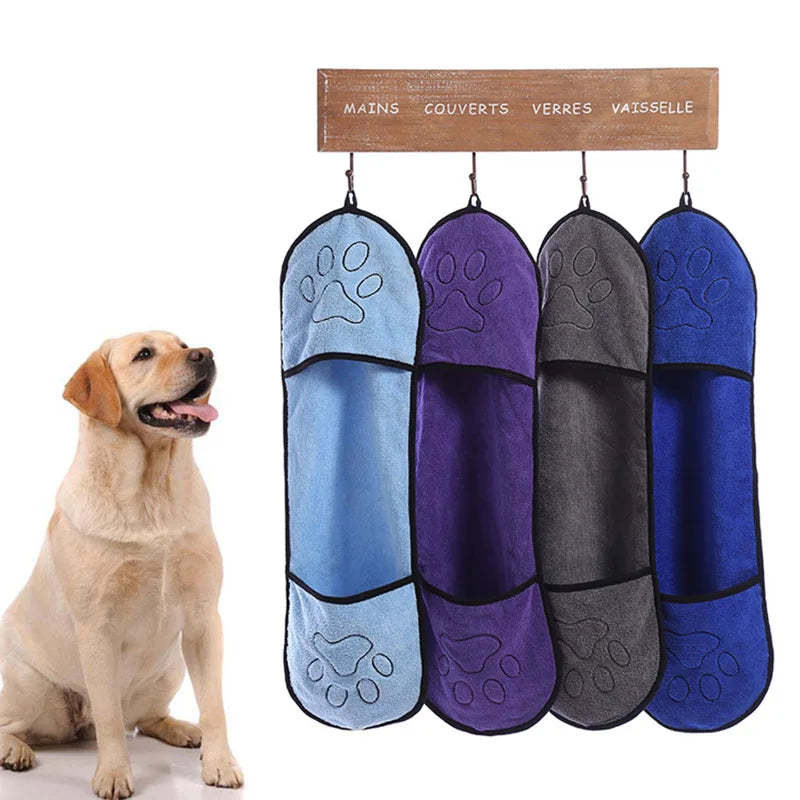Four hanging dog towel sets in blue, purple, gray, and blue with a dog sitting next to them.