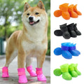 Dog wearing pink rain boots with colorful booties displayed on a white background