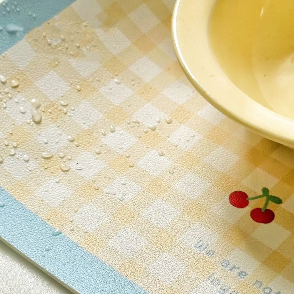 Checkered placemat with a cherry design and a yellow bowl on a checkered tablecloth.