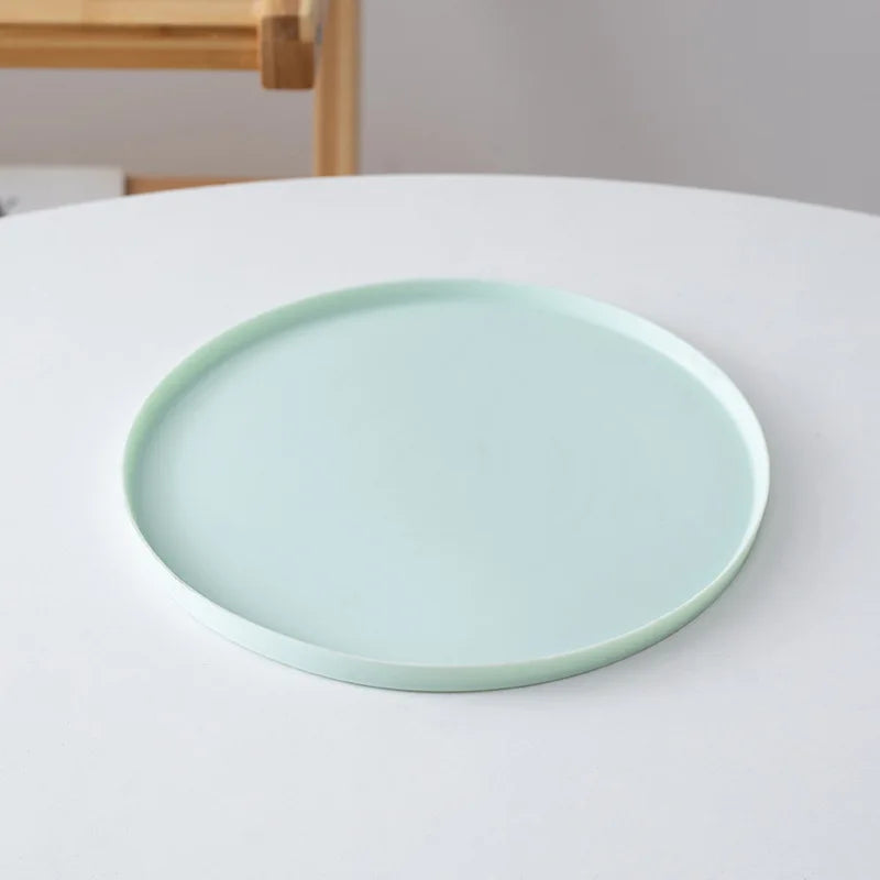 Light green ceramic plate on a white surface with a wooden chair in the background