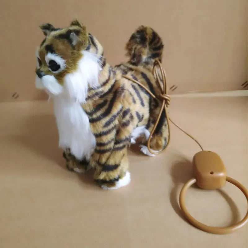 Plush tiger toy with a remote attached  to it  on a tan surface 