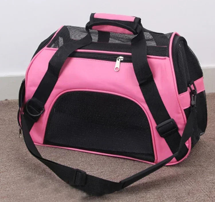 Pink pet carrier with black straps on a carpeted floor