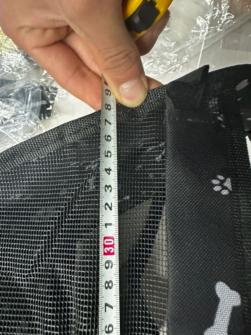 Measuring tape being used to measure a black mesh screen