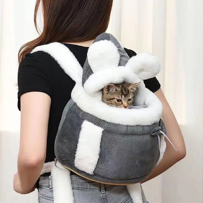 Person carrying a cat in a gray and white pet carrier with bunny ears.
