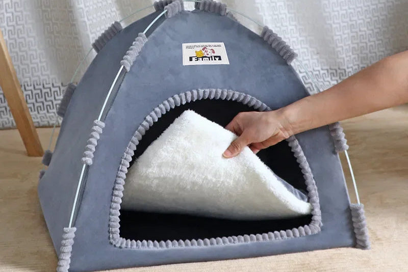 Pet bed with a soft white cushion inside, held by a hand against a light curtain background.