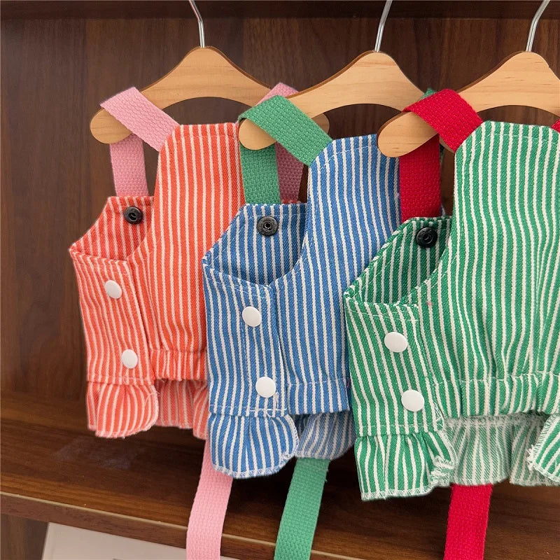 Set of colorful children's overalls on wooden hangers against a wooden background