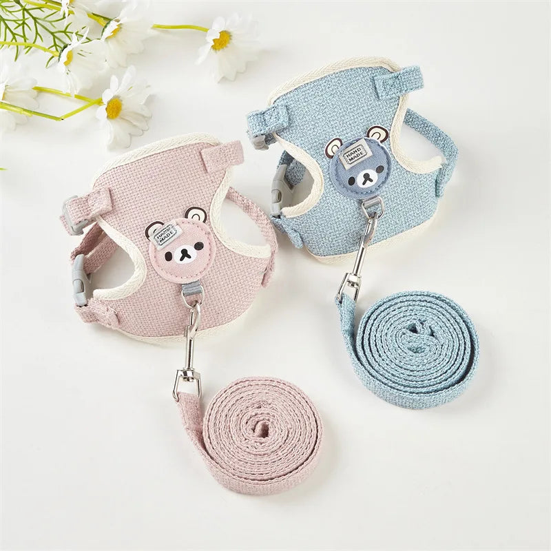 Two pet harnesses, one pink and one blue, with matching leashes on a white background.