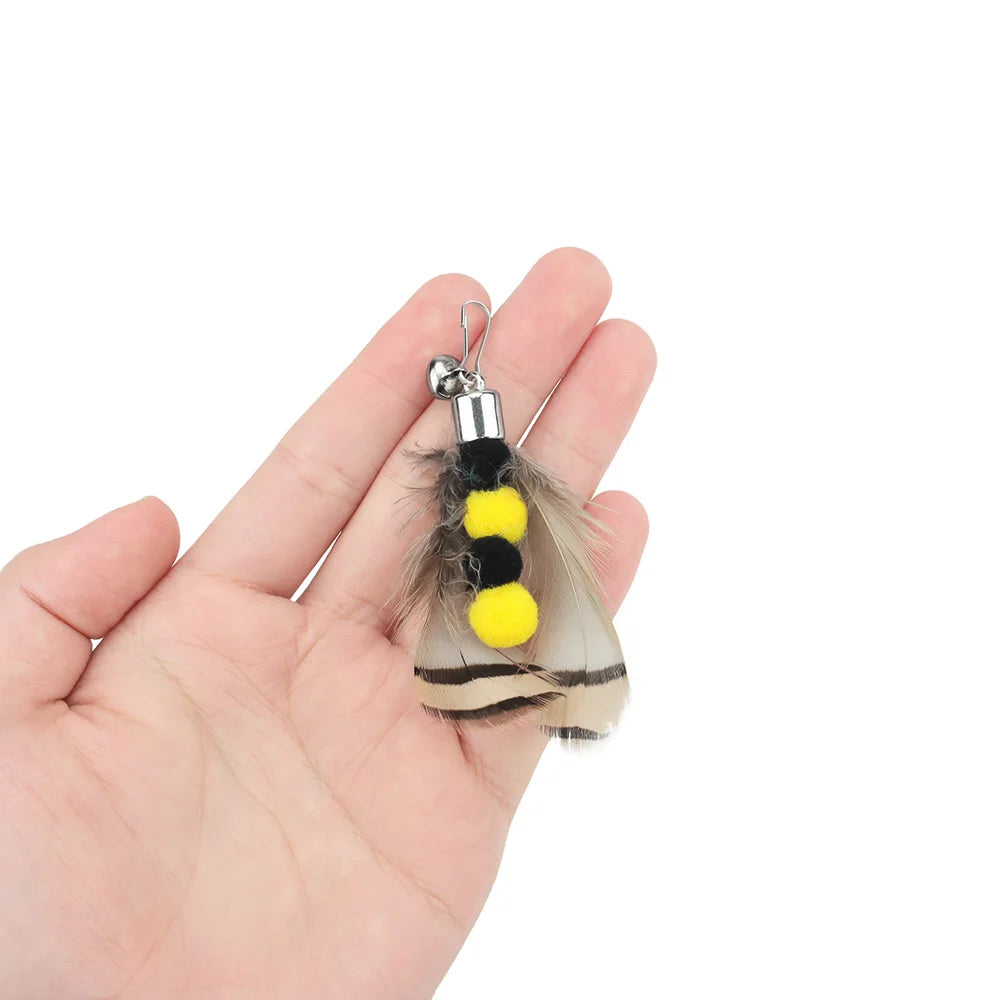 Hand holding a feather keychain with yellow and black pom-poms on a white background