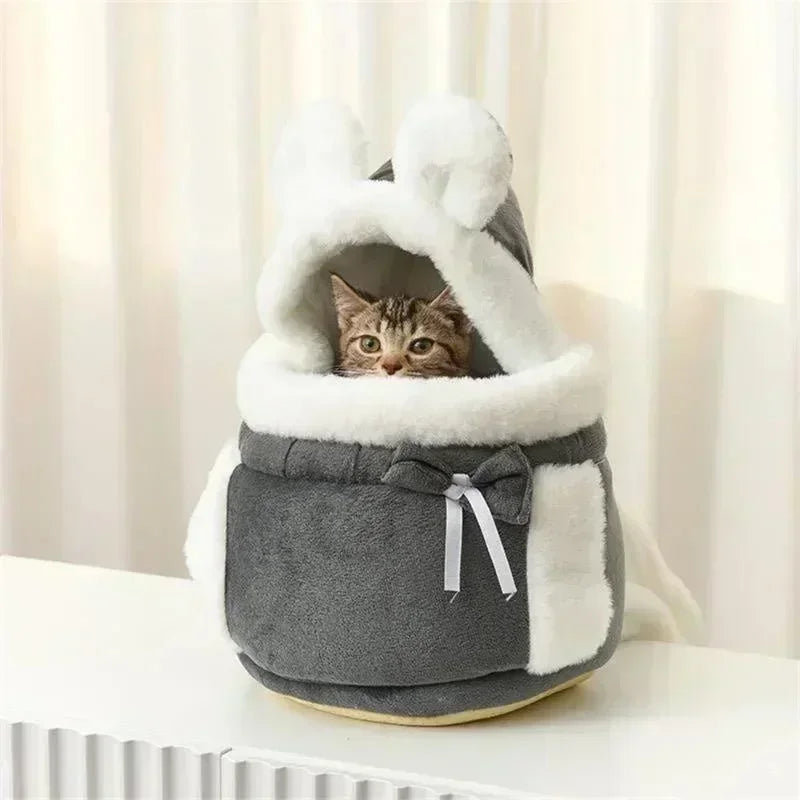 Cat inside a gray and white pet bed with a hood on a light background