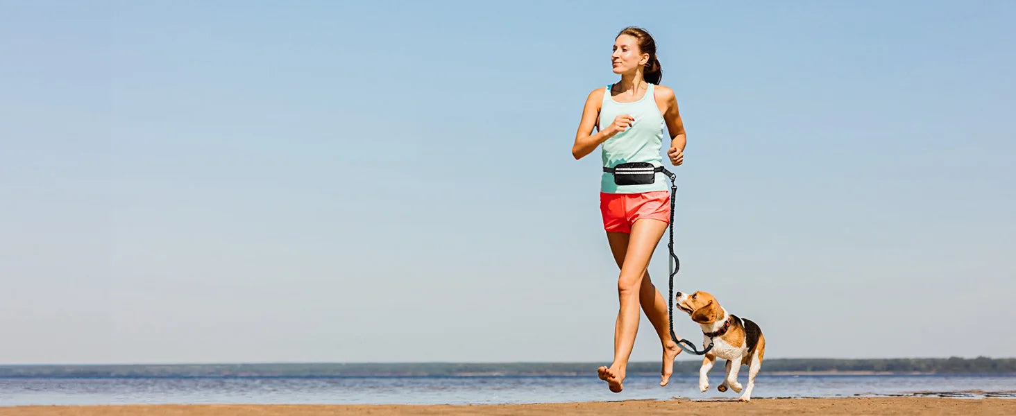 Woman running on a beach with a dog on a leash