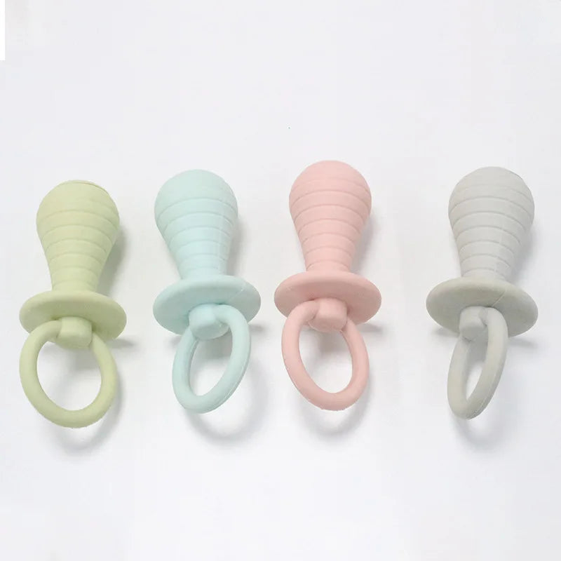 Four baby pacifiers in pastel colors on a white background