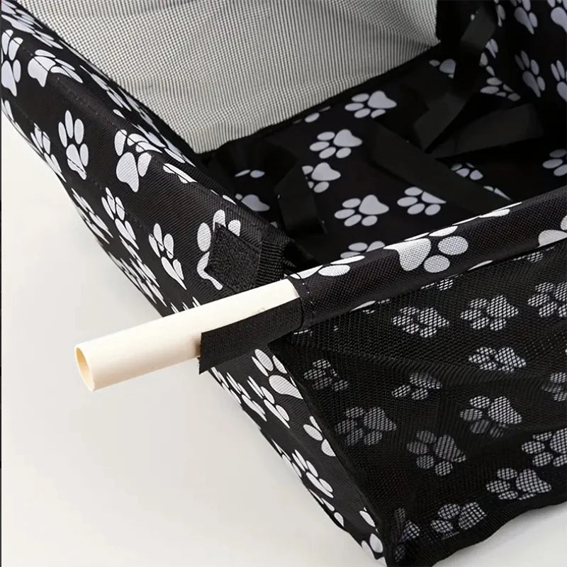 Black pet carrier with white paw prints and a rolled-up white tube inside.