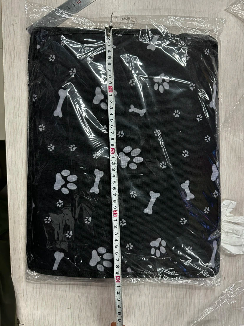 Black pet carrier with white paw prints and bones pattern, measured against a ruler.