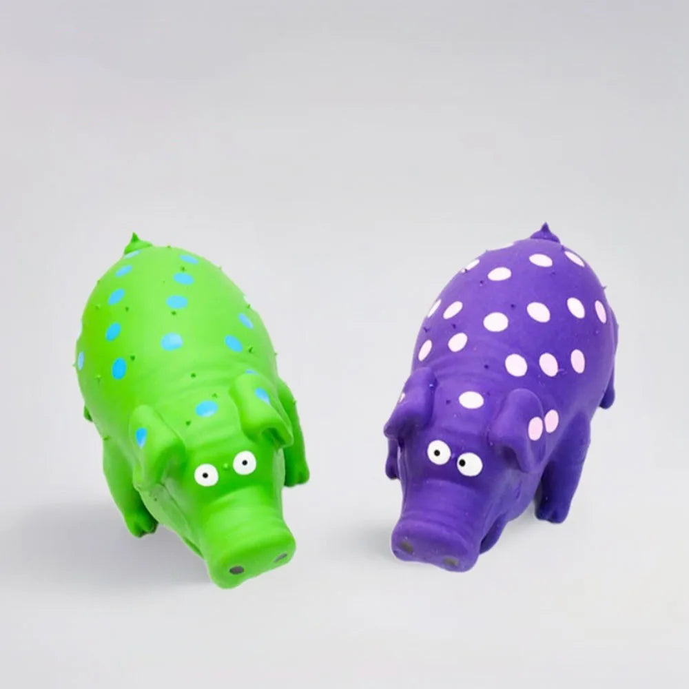 Two pig-shaped toys, one green with blue spots and one purple with white spots, on a light gray background.