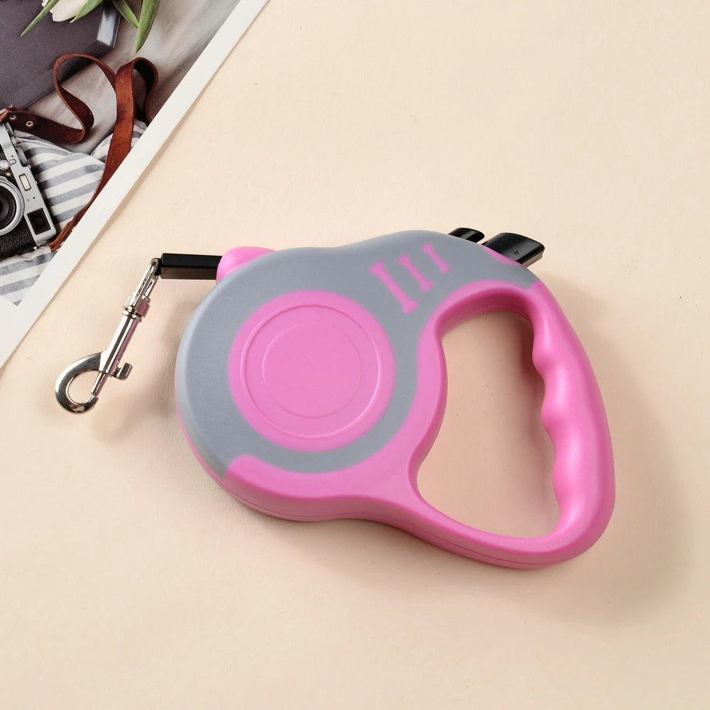 Pink and gray retractable dog leash on a beige surface with a blurred background