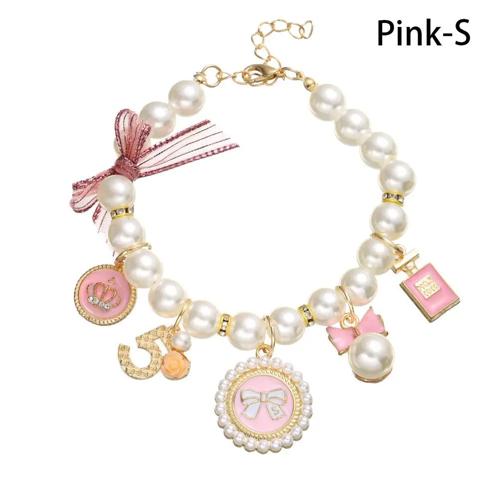 Pearl bracelet with pink and gold charms on a white background
