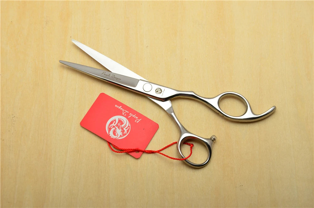 Pair of silver scissors with a red tag on a wooden surface