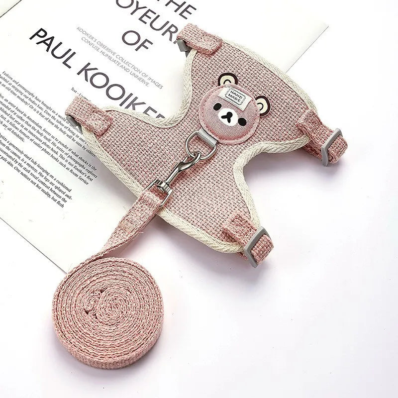 Pink dog harness and leash set on a white surface with a book underneath